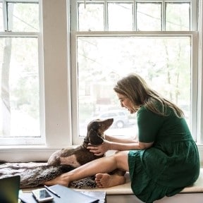 woman and dog on windowsill of house