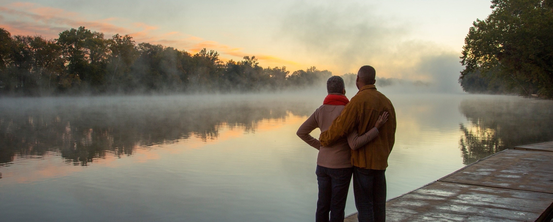 Retired couple standing by lake.