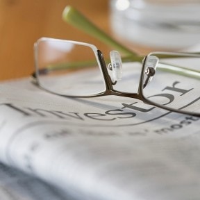 Eyeglasses on top of folded newspaper