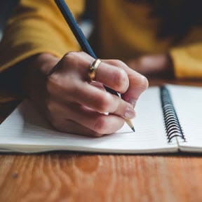 Person writing in notebook. 