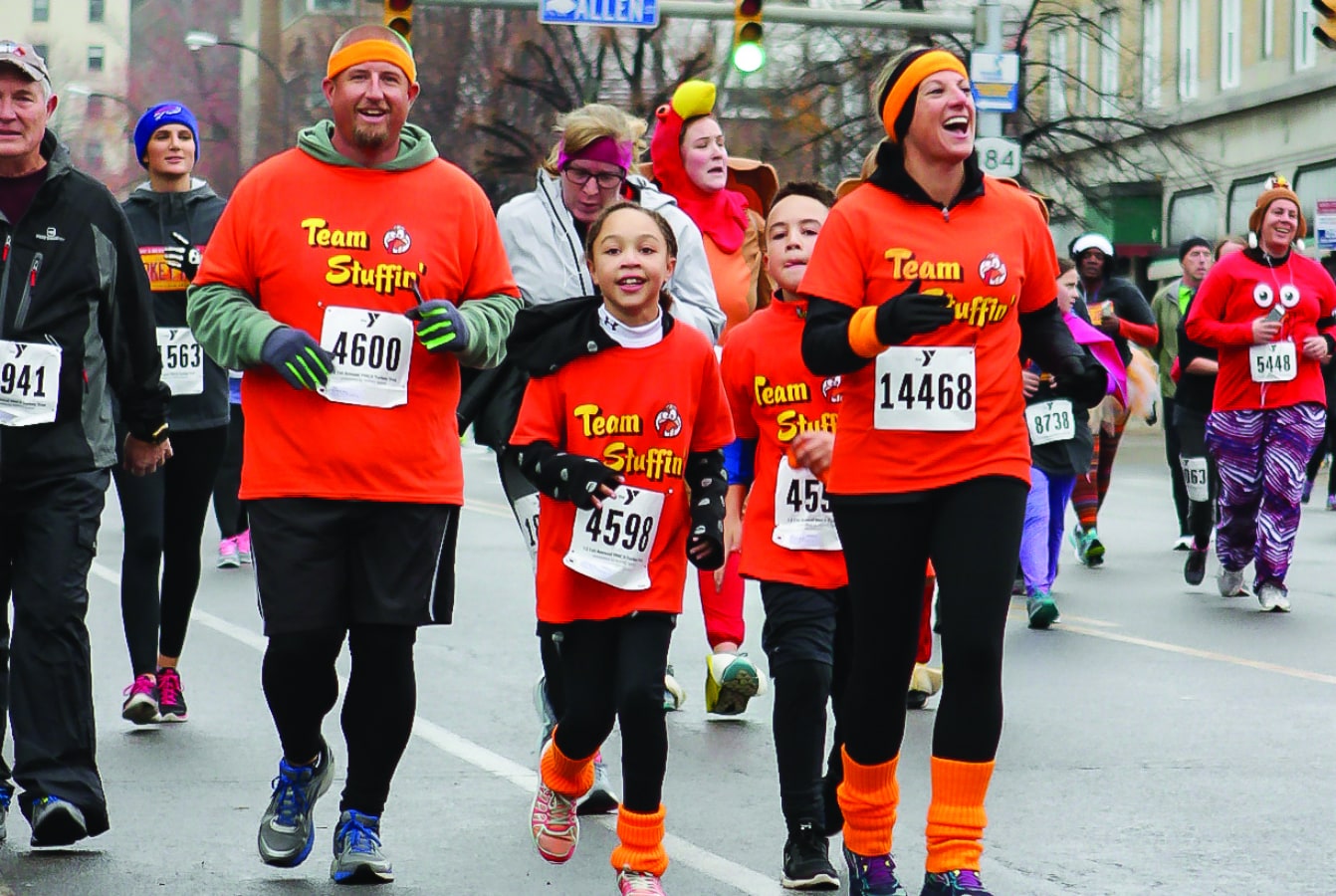 Large group of runners on city street with a “Team Stuffin' ” family in bright red shirts in center