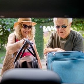 Senior couple packing for road trip.