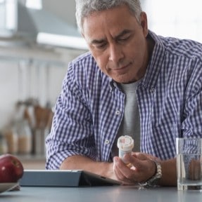 man studying pill bottle