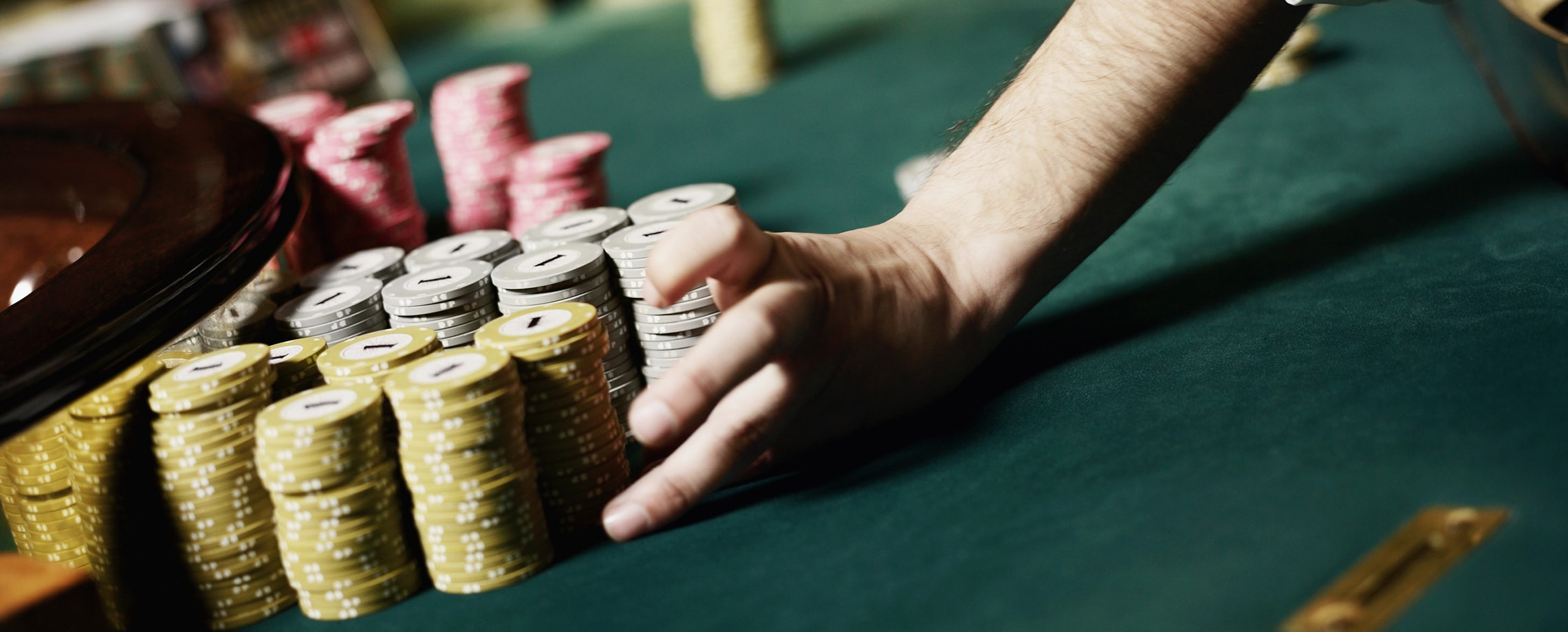 Close up of a person's hand pushing a pile of chips toward a roulette wheel