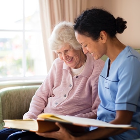 Elderly woman looking at photo album with caretaker