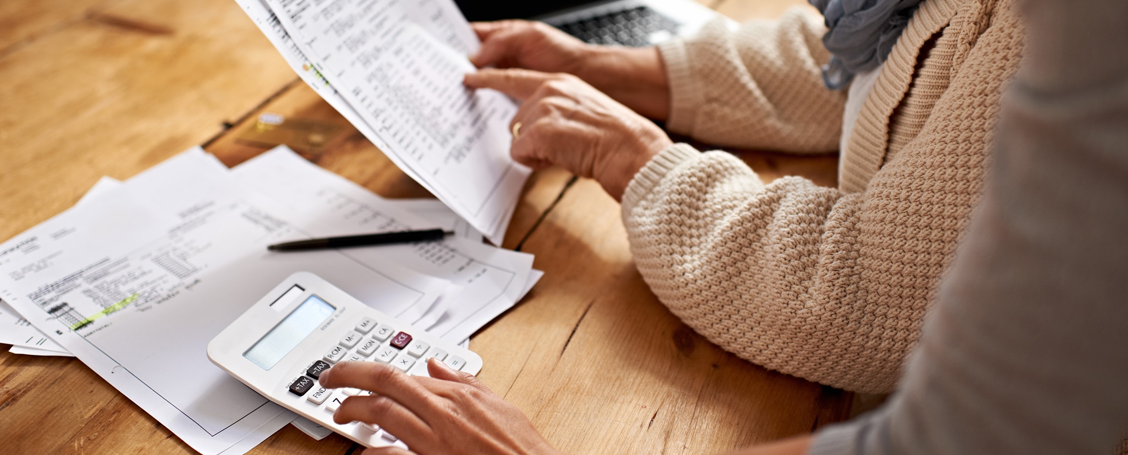Close up of hands with data filled papers and calculator on desk