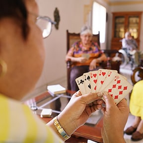 Close up over the shoulder of people playing cards across the room