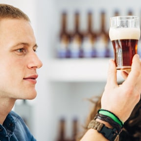 Closeup of twenty something Caucasian male looking at a half glass of beer