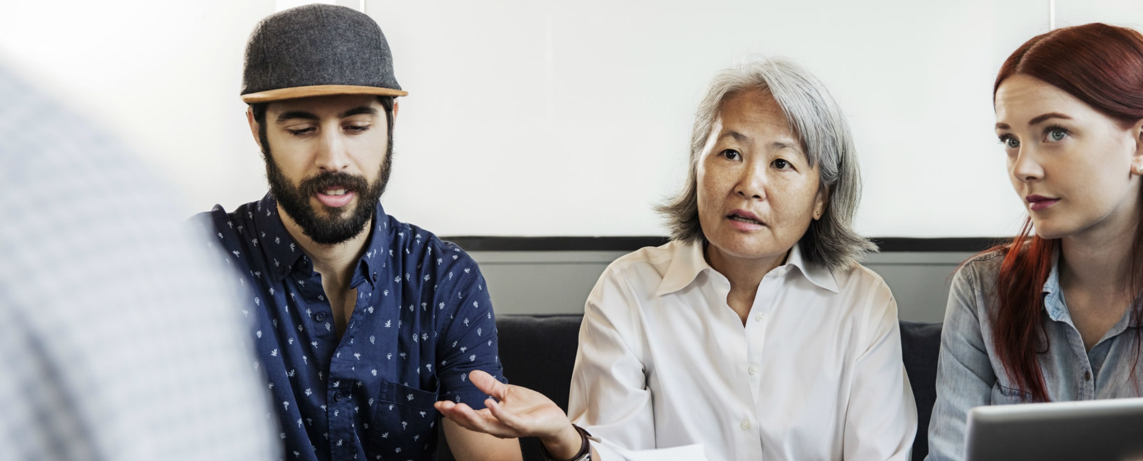 Three people of different races wearing business casual and speaking to someone not shown