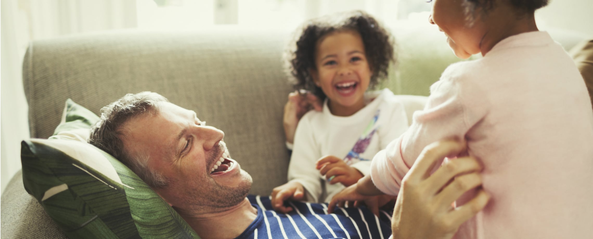 Man lying on couch playing with two children