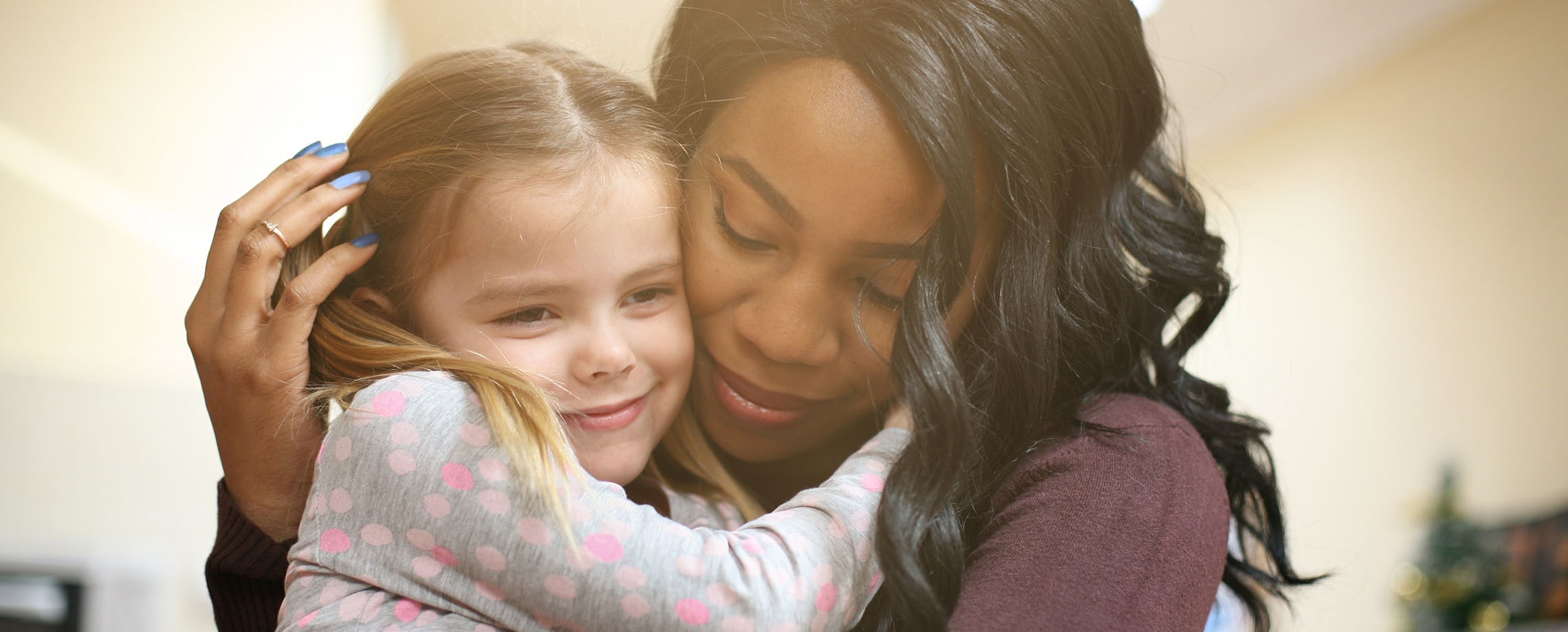 Young Caucasian girl hugging young African-American woman