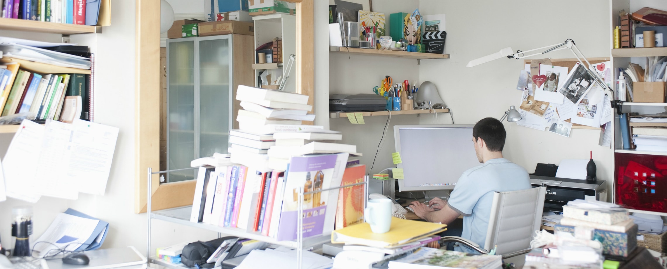 Young man working on a computer in a cluttered office