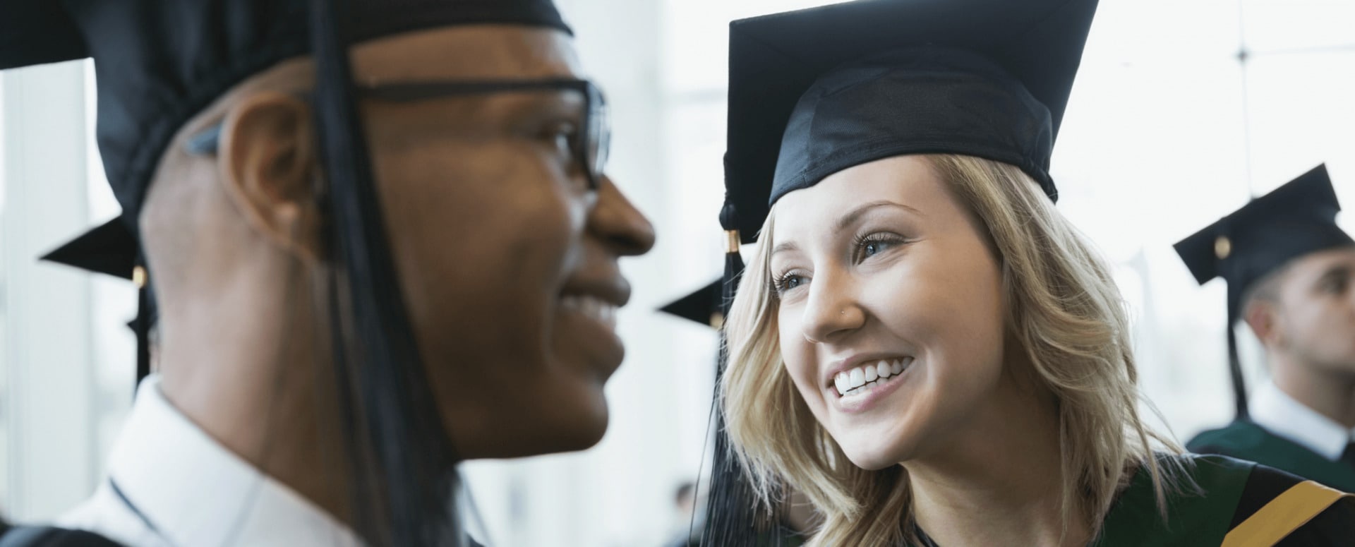 African-American male and Caucasian female graduates in caps and gowns