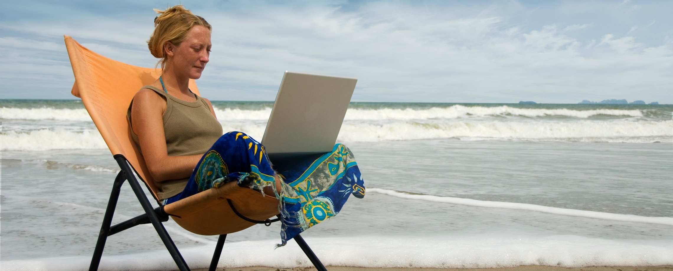 Woman at the beach working on a laptop