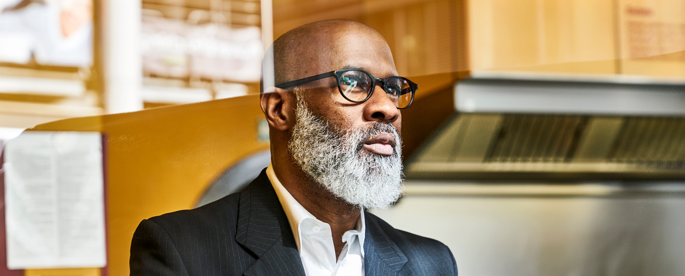 Middle-aged African-American male in suit wearing glasses looking out