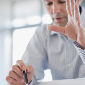 Middle-aged Caucasian man looking down holding a pen reviewing something
