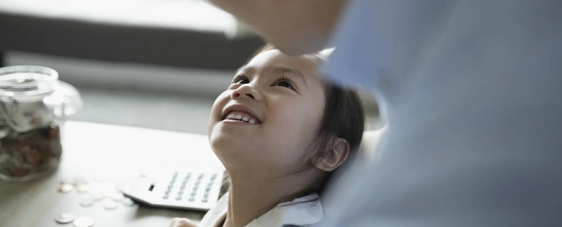 Young Asian girl looking up at her father who's holding her