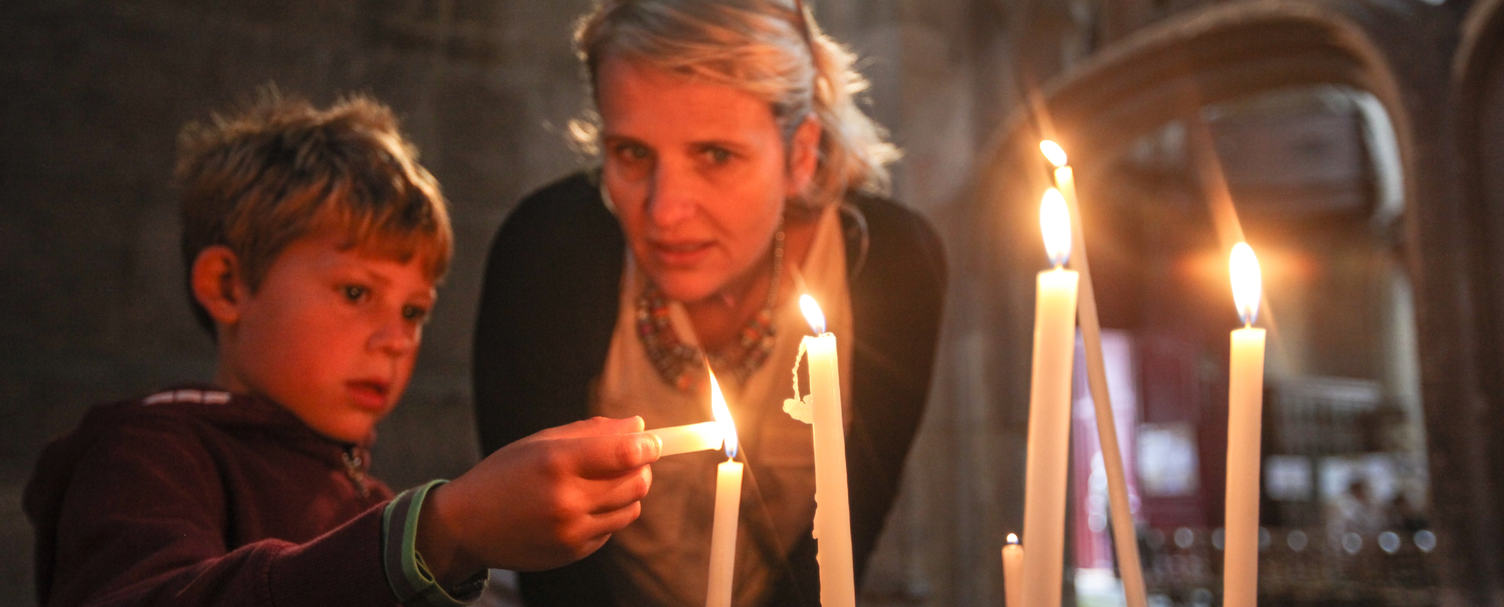Caucasian mother with son lighting candles
