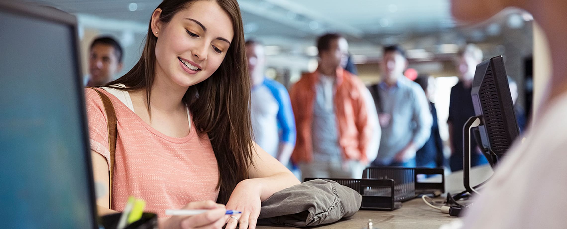 Young woman in queue filling out form at counter
