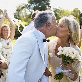 Outdoor wedding of older couple with newlyweds kissing