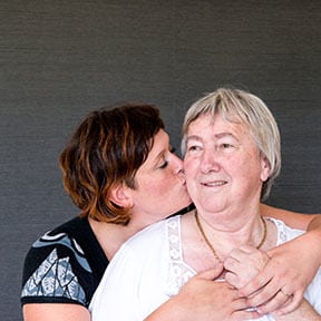 Adult daughter kissing her mother's cheek