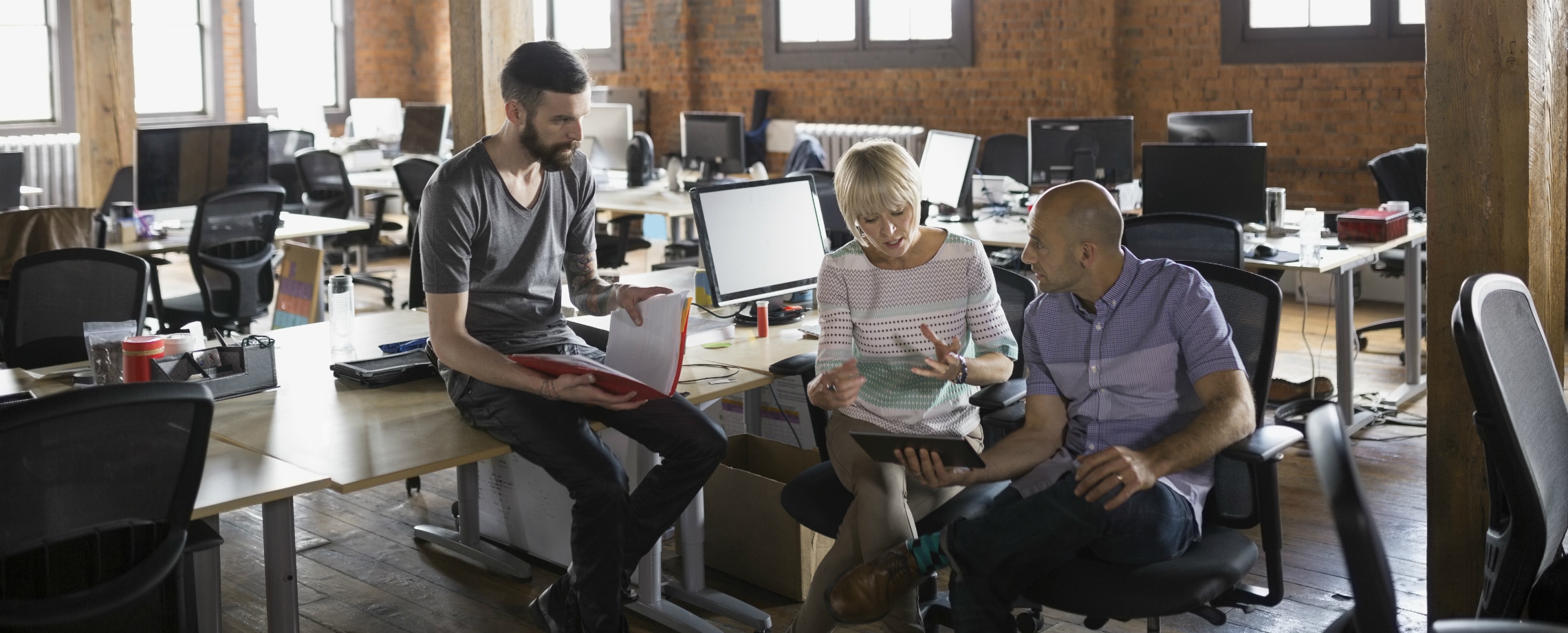 Close up of three coworkers collaborating in a converted industrial office