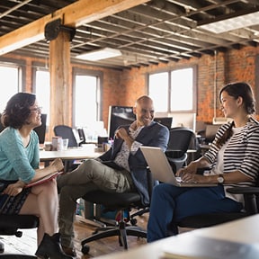 Three businesspeople of different races meeting in converted industrial building office