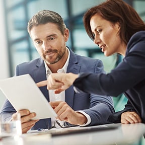 Businesswoman pointing out something on a tablet to a businessman
