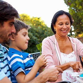 Hispanic grandmother with son and grandson outside at patio table