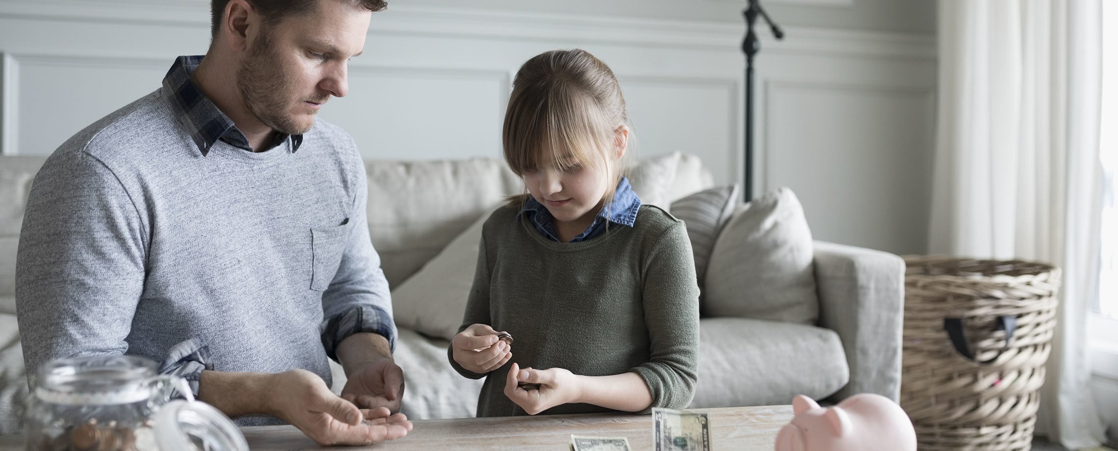 Young girl and her father counting her savings at a table