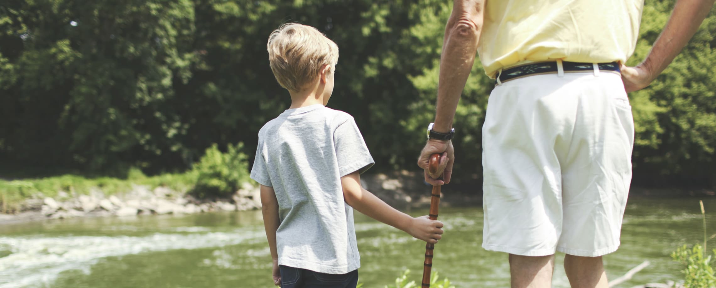 Young boy and elderly man walking beside a stream