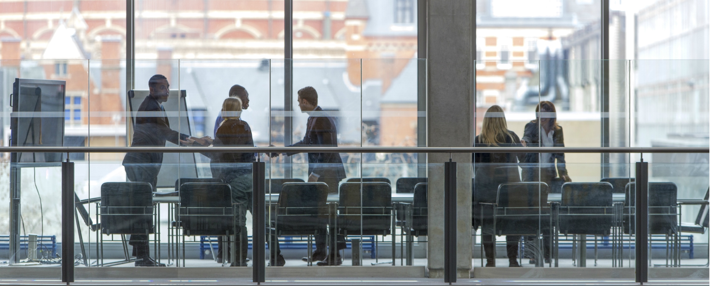 Business people of different races standing and shaking hands over a conference table
