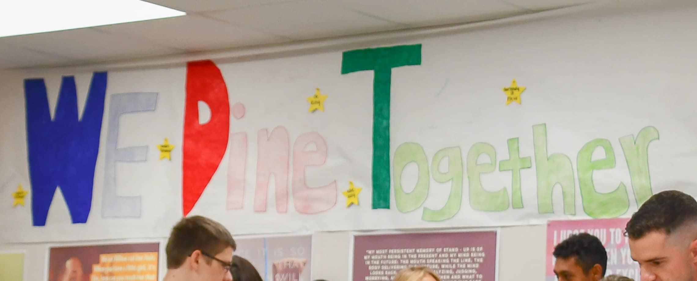 Large sign on wall saying, 'We Dine Together'