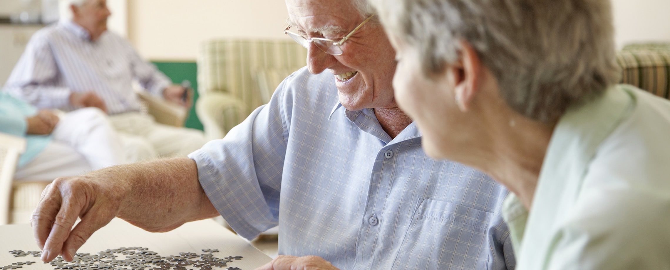 Older Caucasian couple working at a table on a jig-saw puzzle