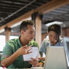 Caucasian businessman and Asian-American businessman looking at laptop together
