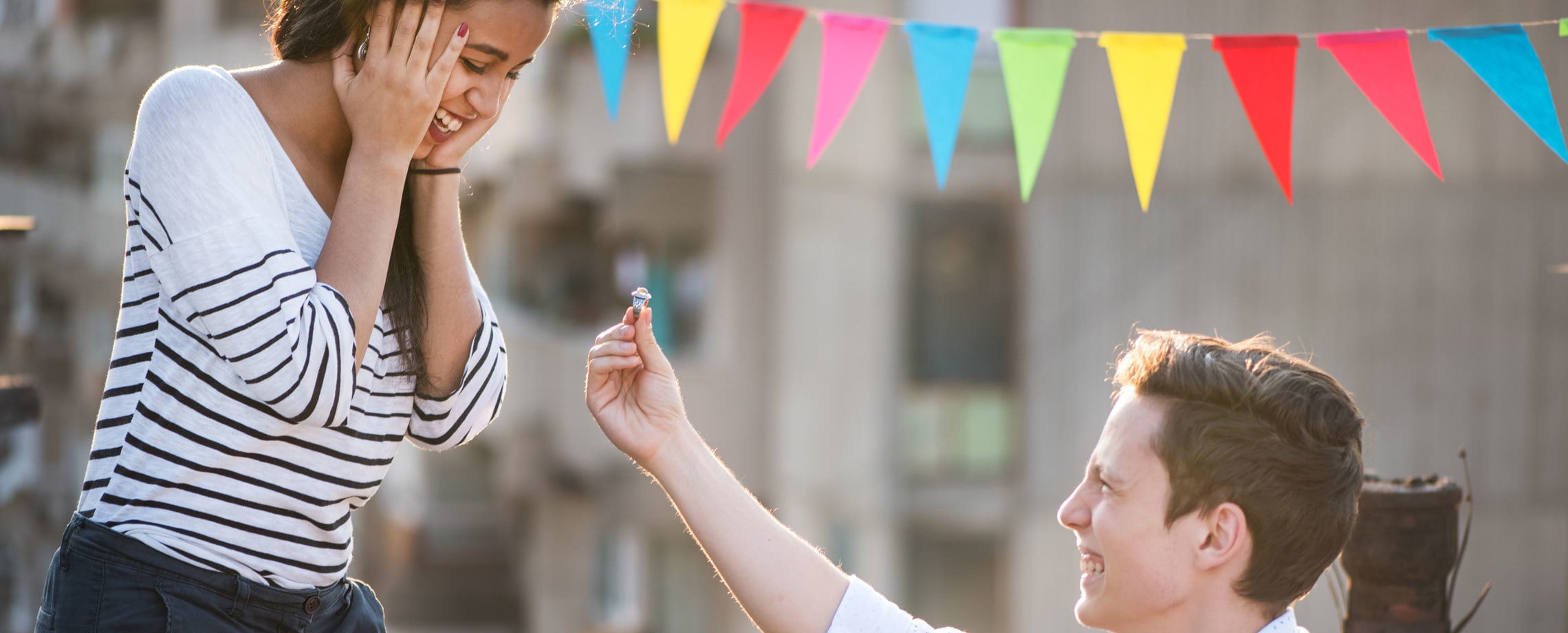Young man on bended knee proposing to girlfriend