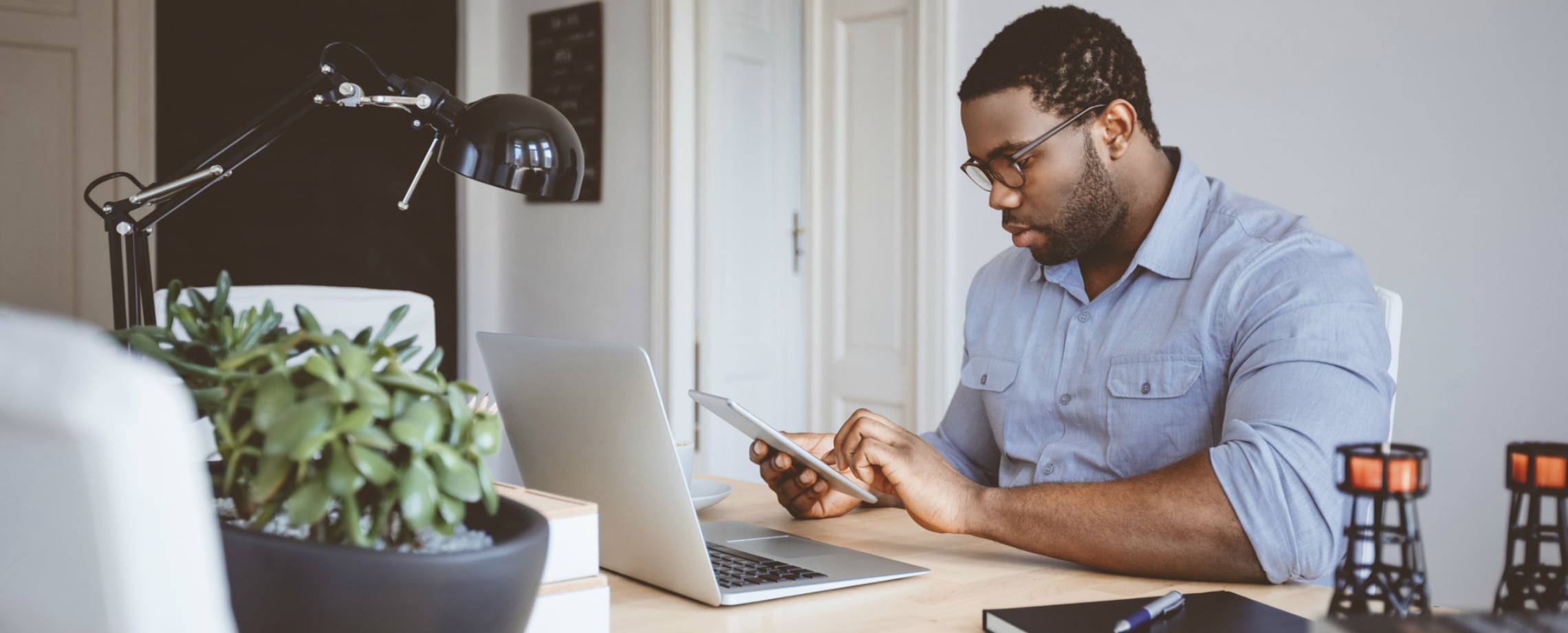 African-American man at desk with laptop and phone