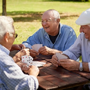 Older men playing cards at picnic table outdoors