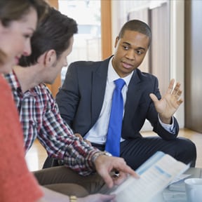 Young African-American man in suit discussing paperwork with a Caucasian couple
