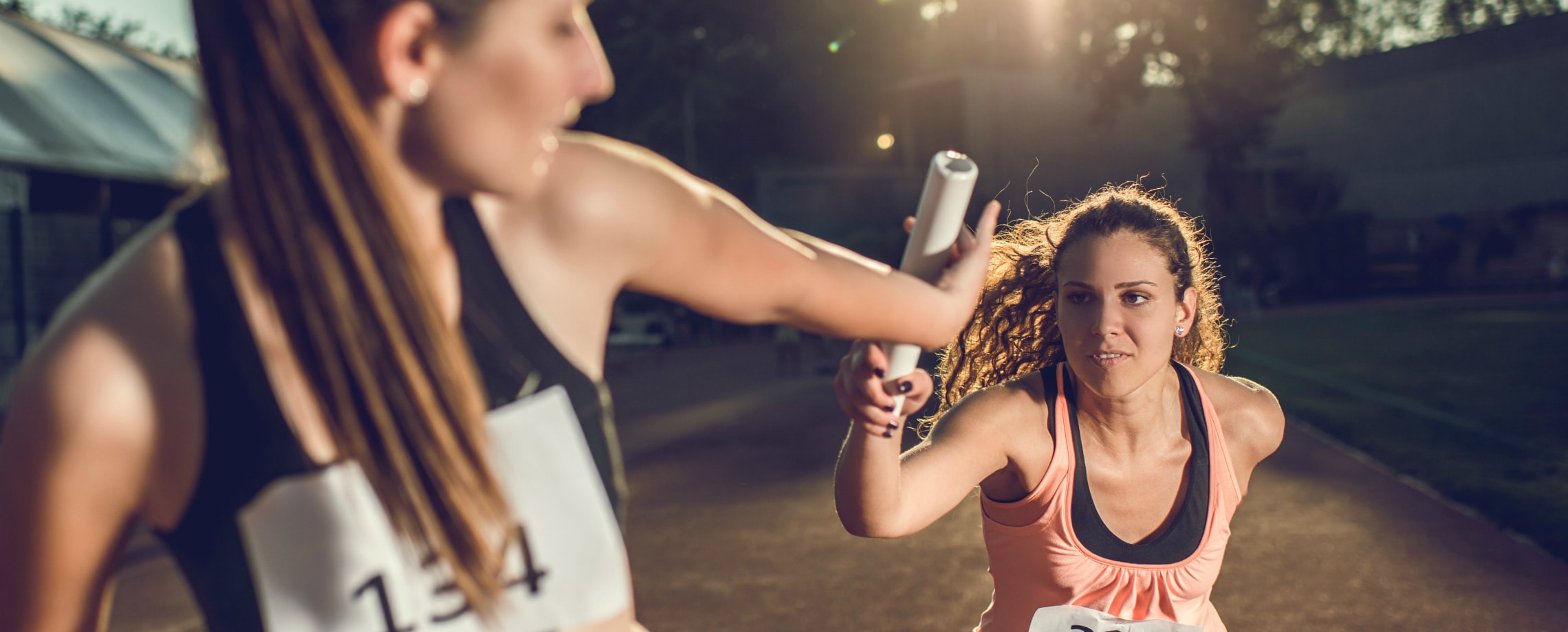 Young woman in relay race passing the baton