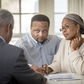 Retirement aged African-American couple listening to an African- American male in suit while reviewing paperwork
