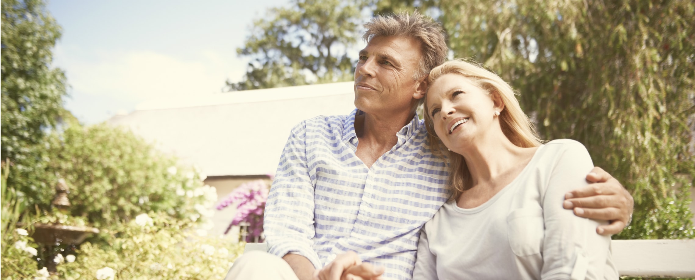 Close up of Middle aged couple sitting outside arm-in-arm and holding hands