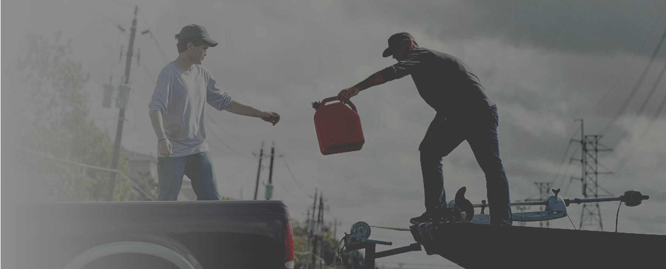 Man on trailer passing a gas can to a person standing in a pickup truck's bed