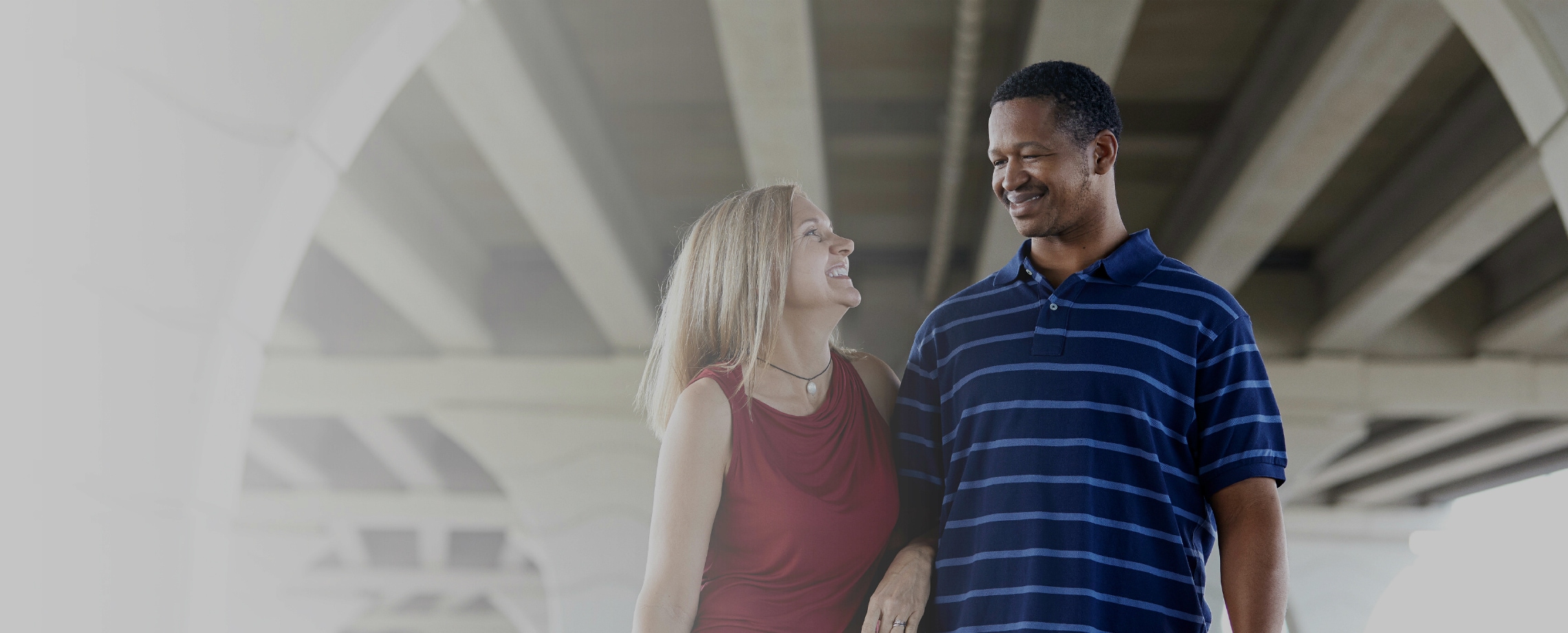 Close up of Caucasian woman smiling with her arm through the arm of an African-American man