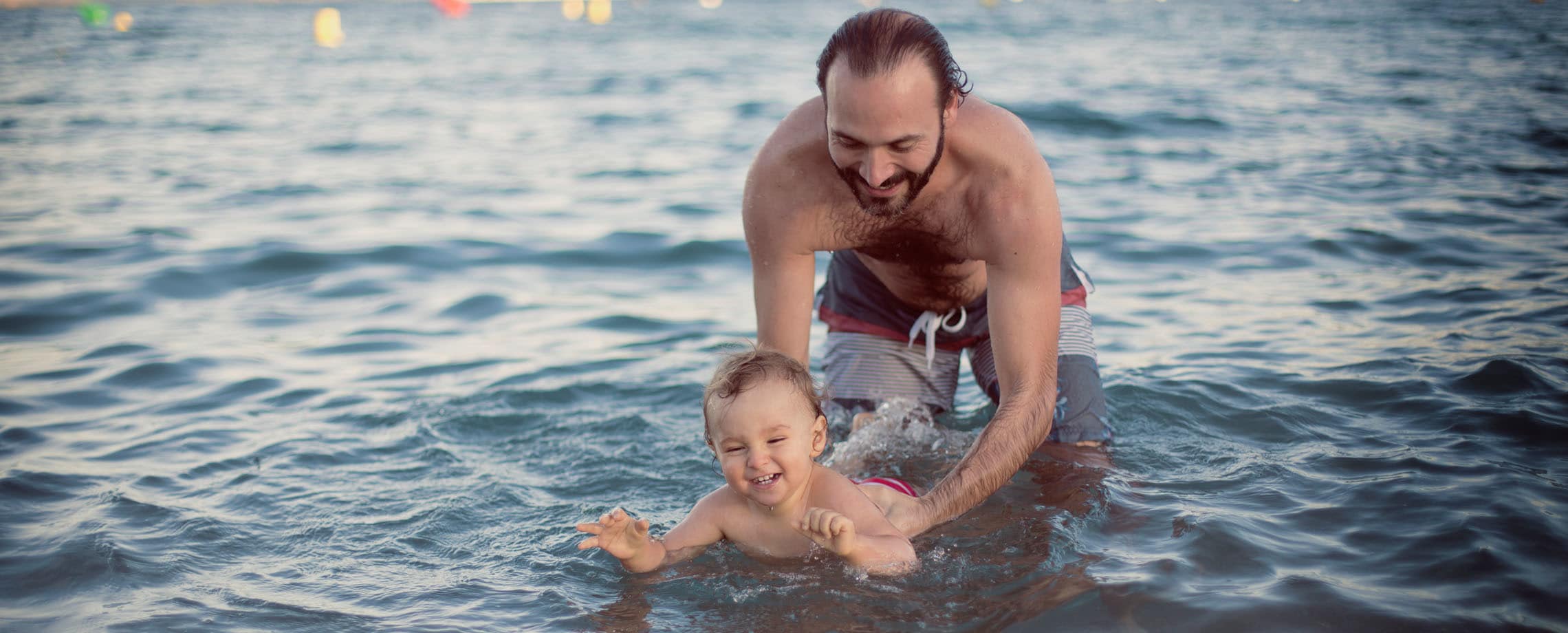 Bearded man teaching his baby to swim