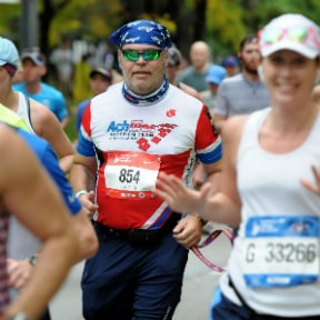 Large group of runners with one colorfully dressed with headscarf and sun glasses