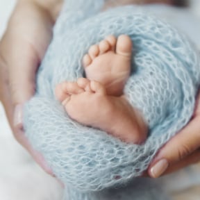 Close up of newborn baby's small feet held in someone's hands