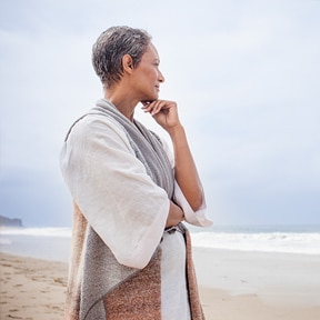 Woman standing on foggy beach looking out to sea