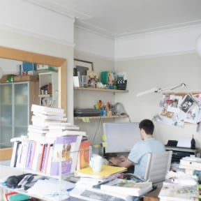 Man working at computer in book and paper cluttered room