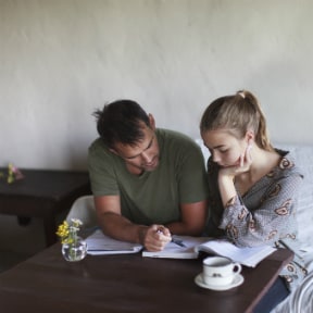 Man pointing out something in a book to a woman in a caf'